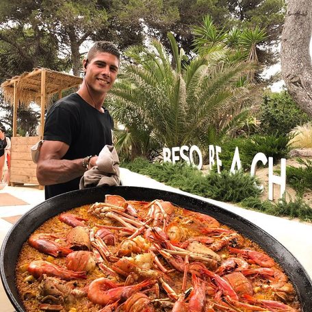 Staff member at Beso Beach holding large pan of food