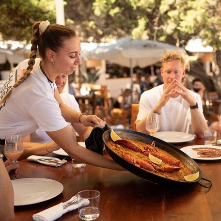 Server with a large platter of food at Cala Bassa