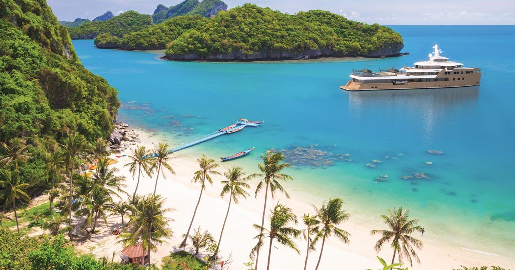 Charter yacht LA DATCHA at anchor in a bay by a paradisiac island