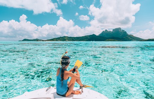 girl sat on the edge of a yacht getting ready to snorkel in clear blue waters of the Caribbean