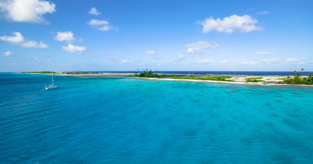 Sailing yacht anchoring in the shallow, turquoise lagoon of Fakarava atoll, Tuamotus archipelago, French Polynesia, south pacific