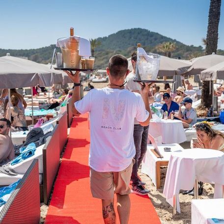 A waiter delivering drinks on red carpet at Nassau Beach Club