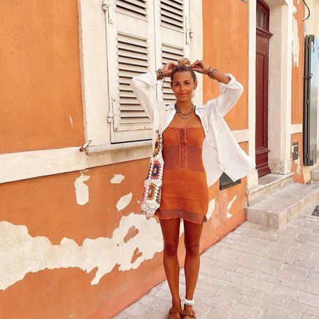 Female charter guest wearing orange in front of orange building